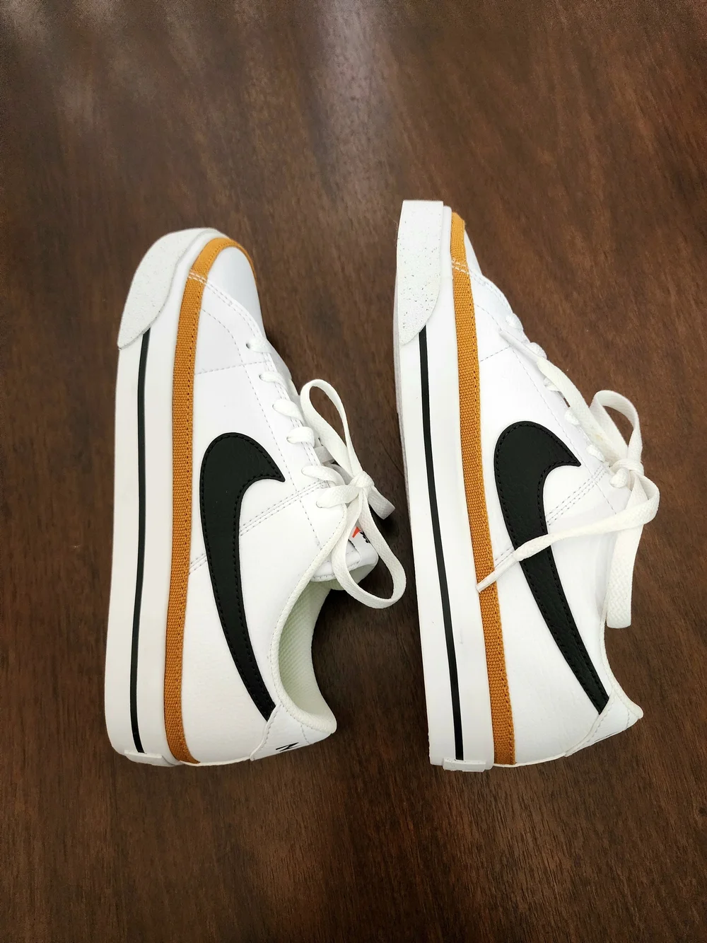 Nike White Low-Top Sneakers with Black Swoosh and Mustard Stripe